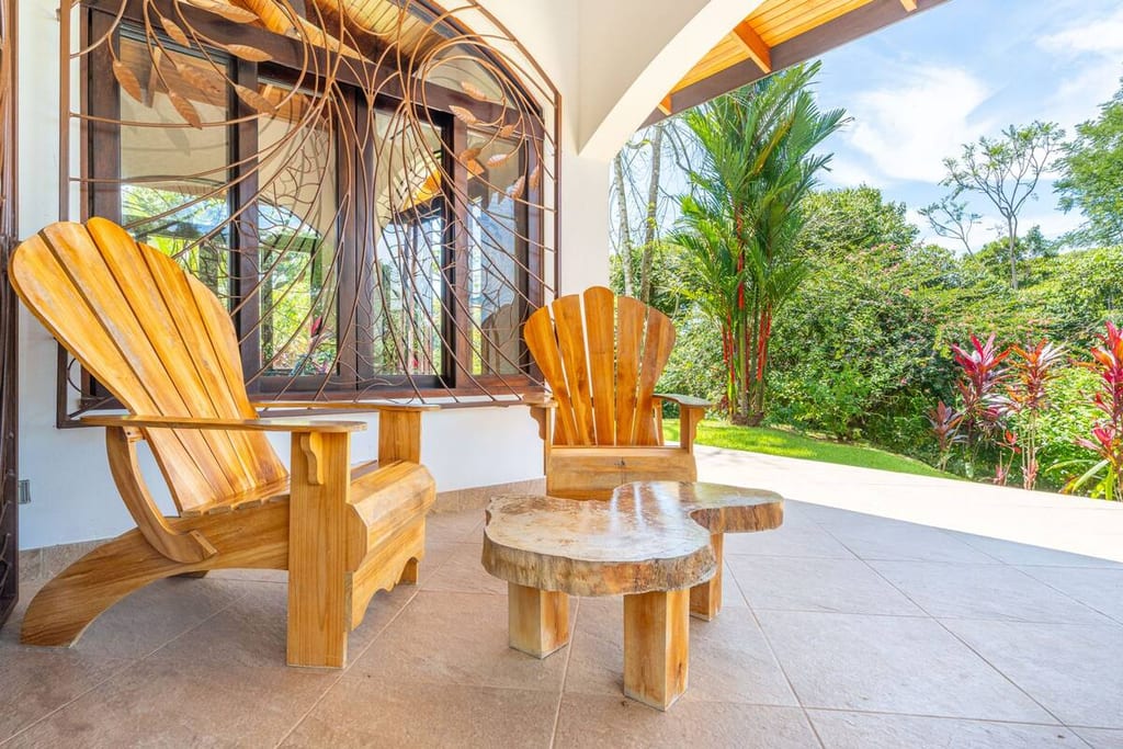 Hand-carved wooden chairs and table on the covered terrace overlooking the garden