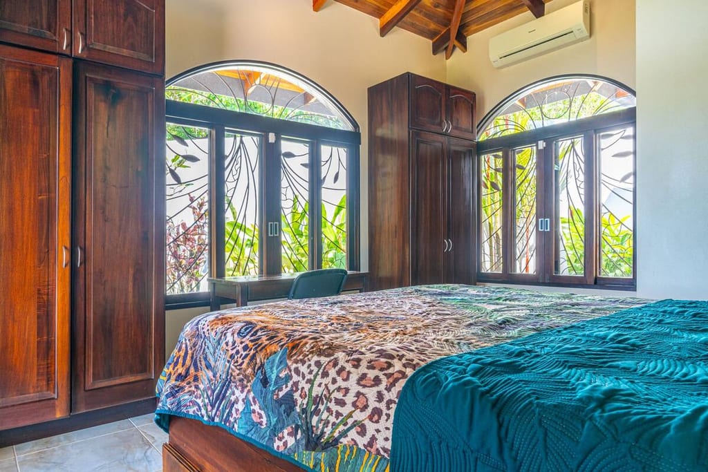 Guest bedroom with queen bed, wardrobe and tall arched windows