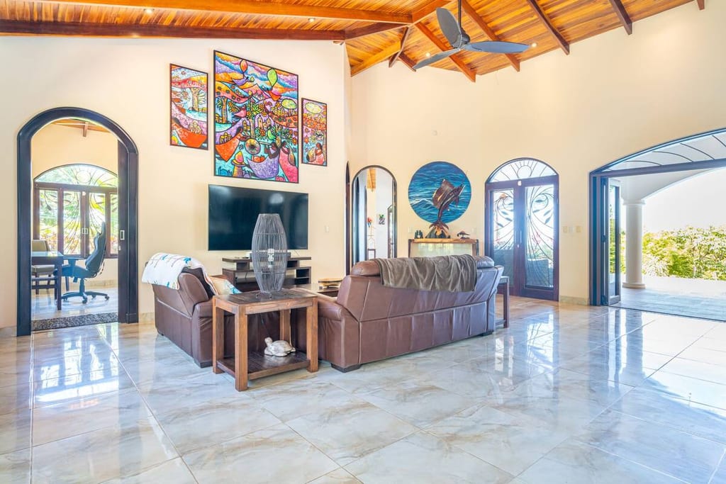 Living room with sofas, 70-inch television and Costa Rican artwork under a vaulted wood ceiling