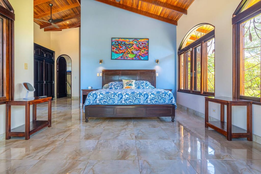King bed in the primary suite with vaulted wood ceiling and garden views