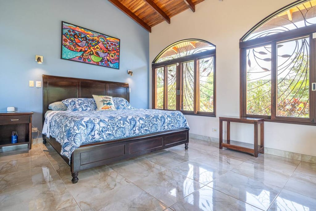 Spacious primary bedroom with king bed, seating and arched windows