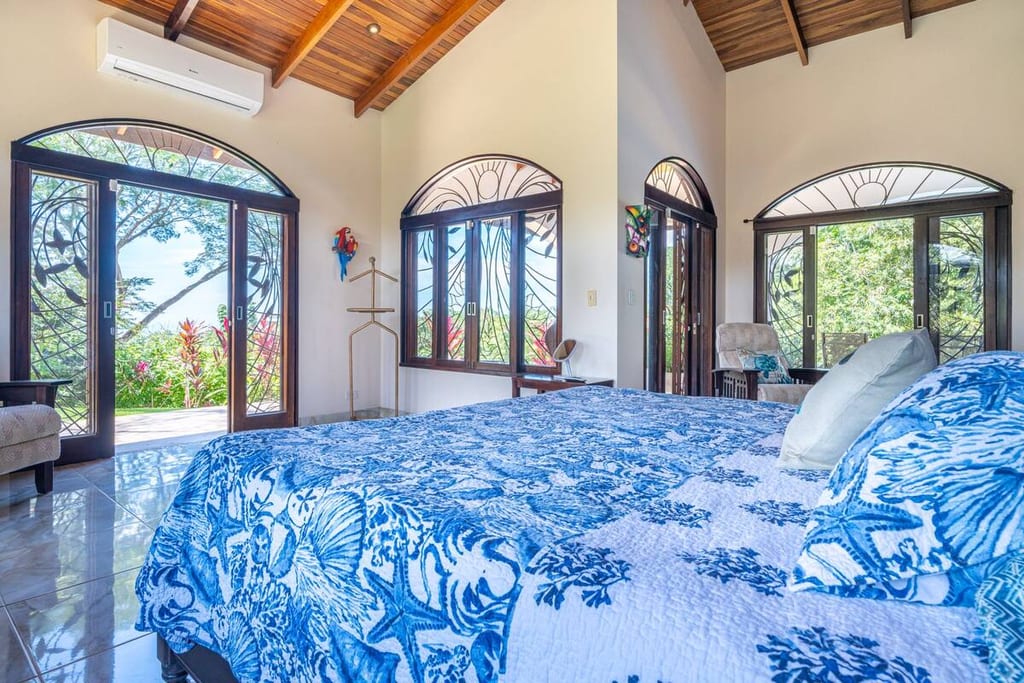 Bedroom with king bed beneath a vaulted hardwood ceiling and arched windows