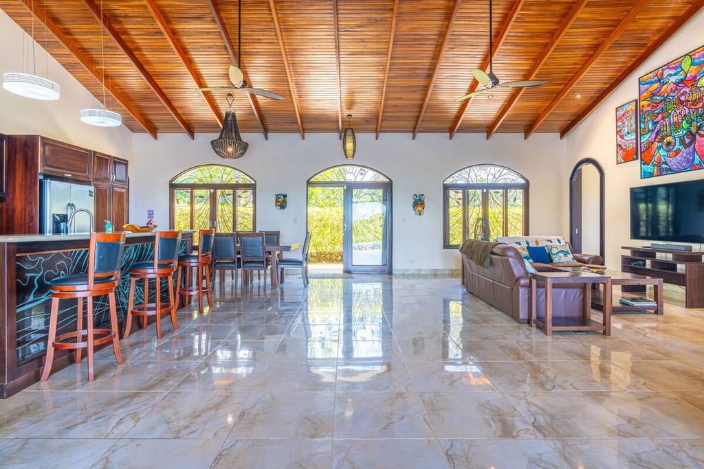 Open-plan great room with vaulted hardwood ceiling, bar seating and ocean views
