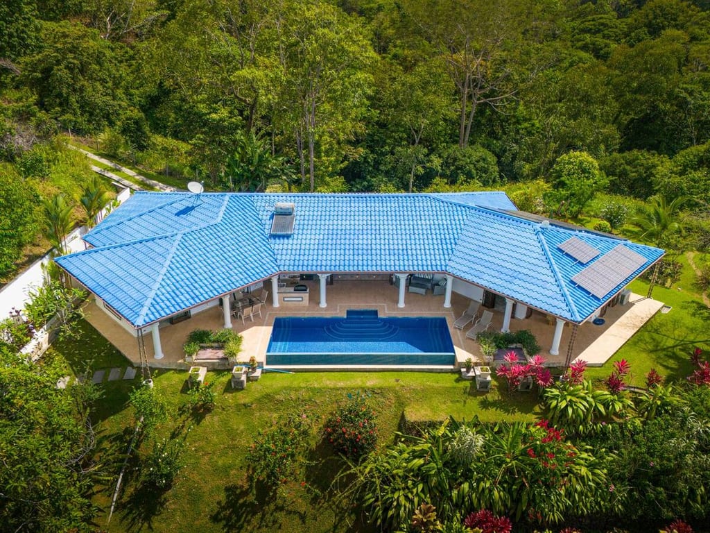 Aerial view of Casa Rosa Blanca, its blue tile roof and infinity pool surrounded by rainforest in Ojochal, Costa Rica