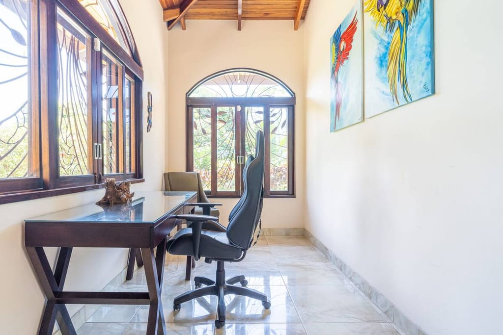 Dedicated home office with desk, ergonomic chair and macaw artwork