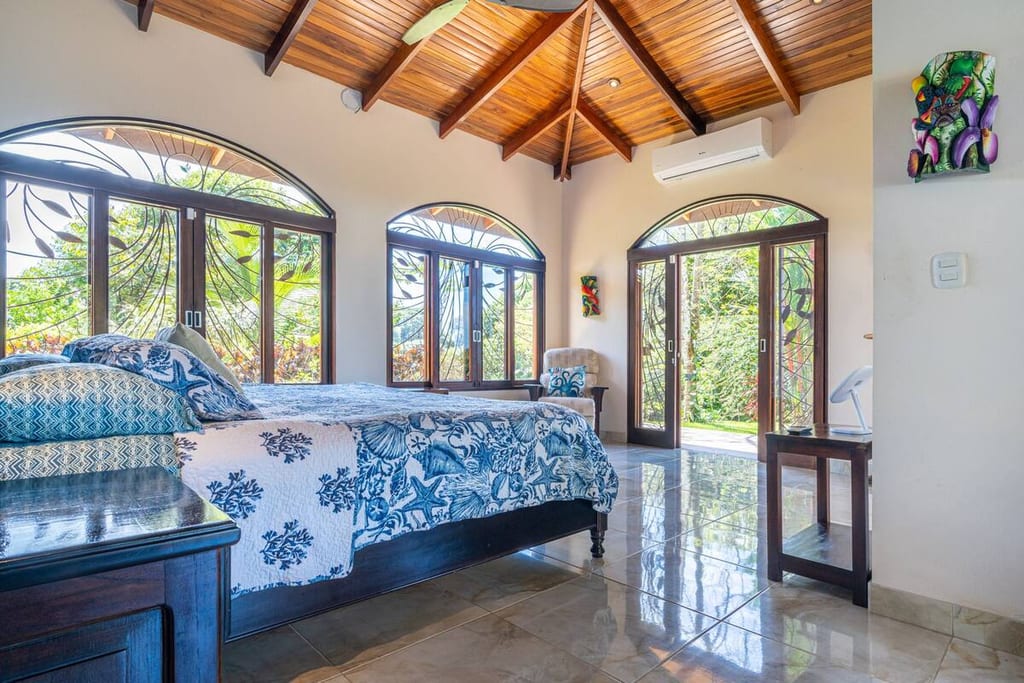 Primary bedroom with king bed, arched windows and doors opening to a private porch