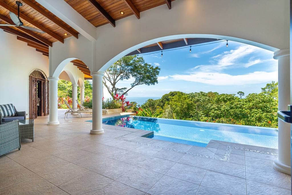 Pacific ocean view framed by the villa's arches, looking out over the infinity pool and rainforest canopy